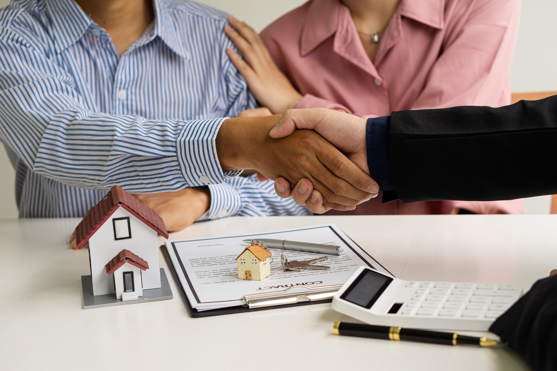 The sales representative shakes hands and hands the keys to the new homeowner after the sale contract is complete. A businessman offers a contract to purchase a house for the purchase of real estate or an apartment to customers.